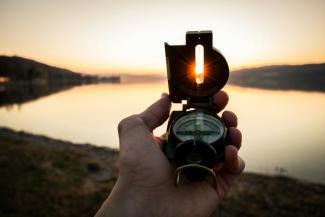 person showing black and white compass by Tim Graf courtesy of Unsplash.