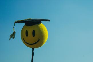 a smiley face wearing a graduation cap by Rohit Tandon courtesy of Unsplash.